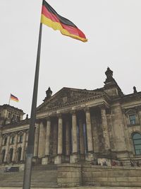 Low angle view of the reichstag and german flag against sky