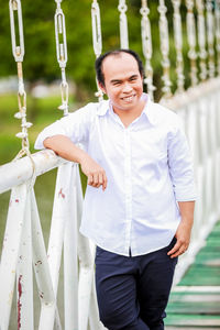 Portrait of smiling man standing on footbridge