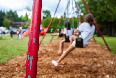 Rear view of children playing on swing in park