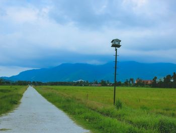 Road amidst field against sky