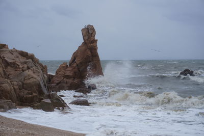 Rock formation on beach against sky