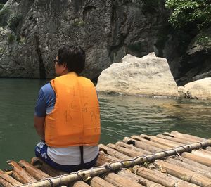 Rear view of man sitting on rock