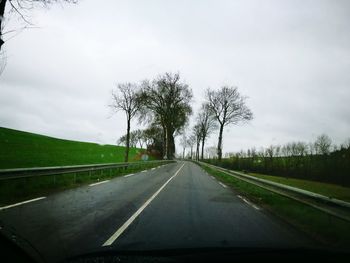 Road by trees against sky
