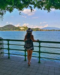 Rear view of woman standing by railing against sky