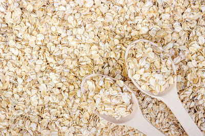 Pile of oat flakes and wooden spoon on oat flakes background