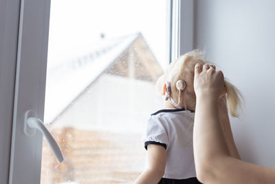 Young woman looking through window