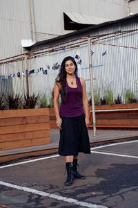 Full length portrait of young woman standing against building