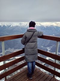 Rear view of woman standing on snowcapped mountain