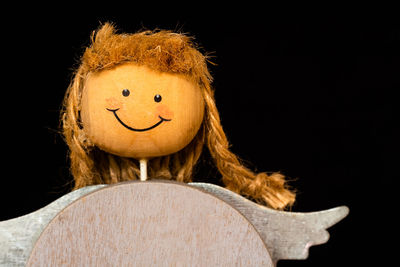 Close-up portrait of smiling toy against black background