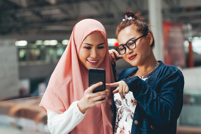 Smiling women sharing smart phone