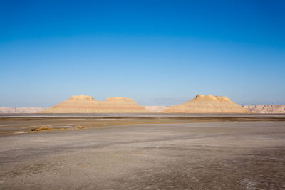 Scenic view of desert against clear blue sky