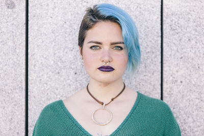 Portrait of young woman against wall