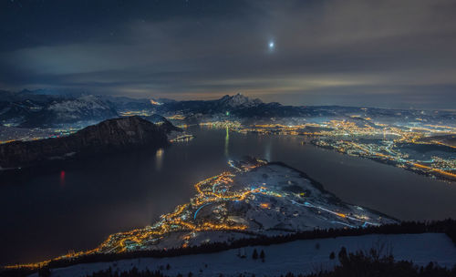 Aerial view of lake by snowcapped mountains against sky at night