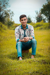 Portrait of young man sitting on field