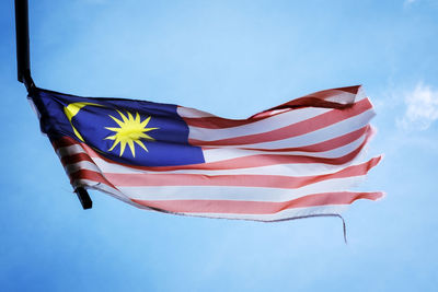 Low angle view of flag against blue sky