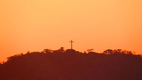 Silhouette cross against sky during sunset