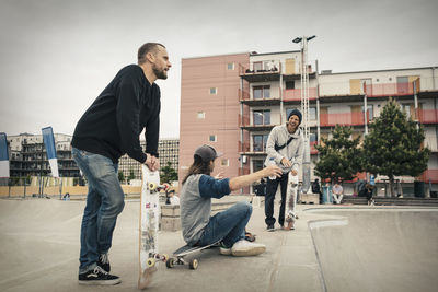 Happy male friends spending leisure time at skateboard park