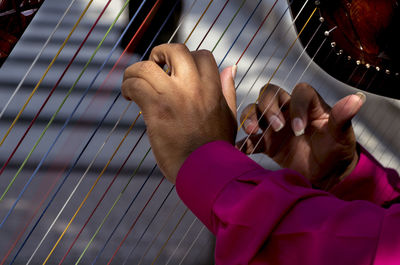 Cropped hands of man playing harp