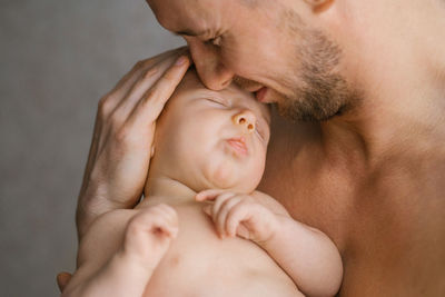 A happy caucasian father holds his baby son in his arms and kisses him with care