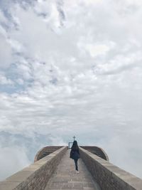 Rear view of woman standing on observation point against cloudy sky