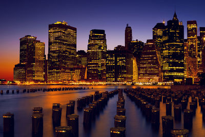 Illuminated modern buildings in city against sky at night