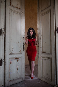 Portrait of woman standing against door