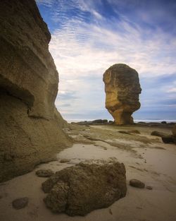 Rock formation on beach against sky