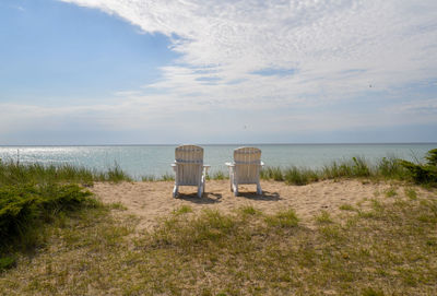 Empty white lawn chairs on the beach