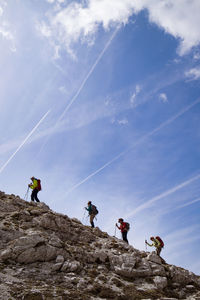 Hikers walking across mountain against sky