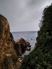 Scenic view of rocks by sea against sky