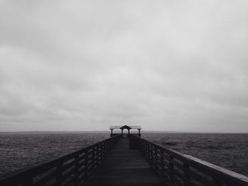 Pier on sea against cloudy sky