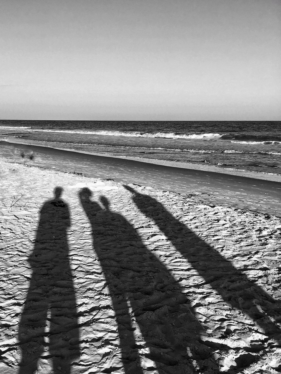 SHADOW OF PEOPLE ON BEACH AGAINST SKY