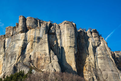 Low angle view of rock formation against clear blue sky