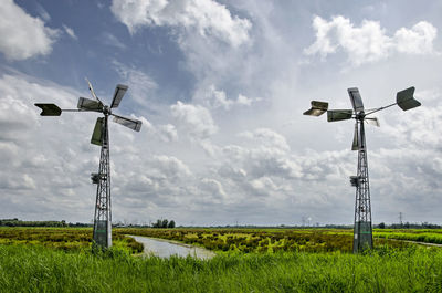 Two small modern windmills in a landscape with swamps and meadows under a sky with scattered clouds