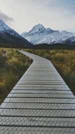 Footpath leading towards mountain range against sky