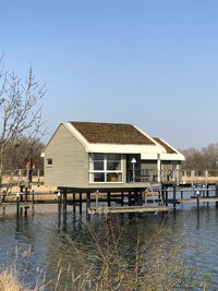 Houses by lake against clear blue sky