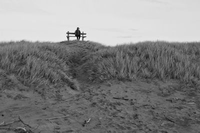 Man walking on field against sky