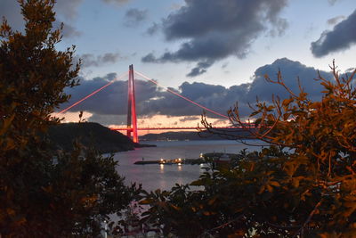 Suspension bridge over river against sky during sunset