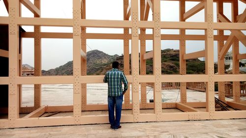 Rear view of mature man standing by built structure