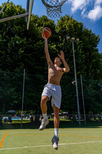 Young caucasian basketball player athlete in action jumping on artificial turf playing field