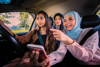 Young woman using smart phone in car