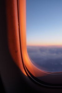 Close-up of airplane window against sky during sunset