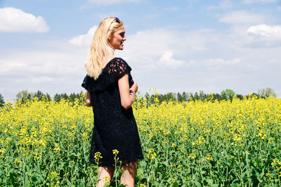 Smiling young woman standing on oilseed rape field