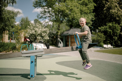 Full length side view of happy boy with down syndrome enjoying seesaw at park