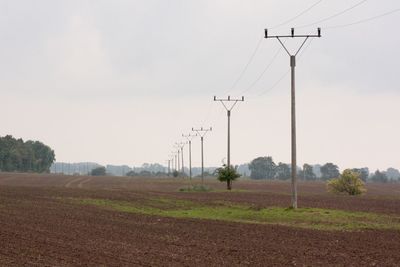 Electricity pylon on field against sky