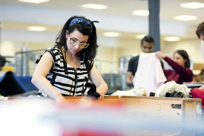 Serious mature volunteer working at workshop with man and woman in background