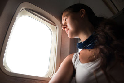 Low angle view of woman looking through window while sitting in airplane