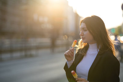 Thoughtful beautiful woman holding flavored ice in city