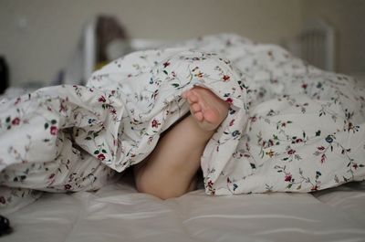 Low section of baby sleeping on bed