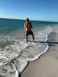 Full length of shirtless man at beach against sky